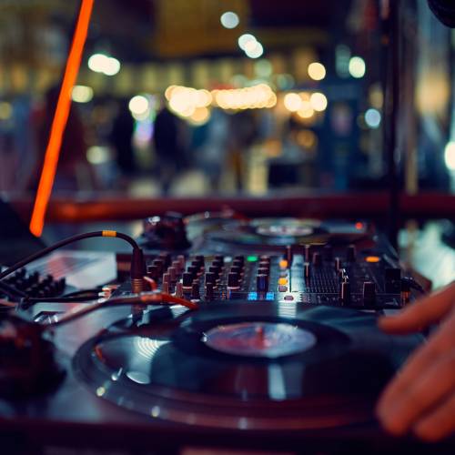 turntable, hand of dj on the vinyl record at night club. blured background.